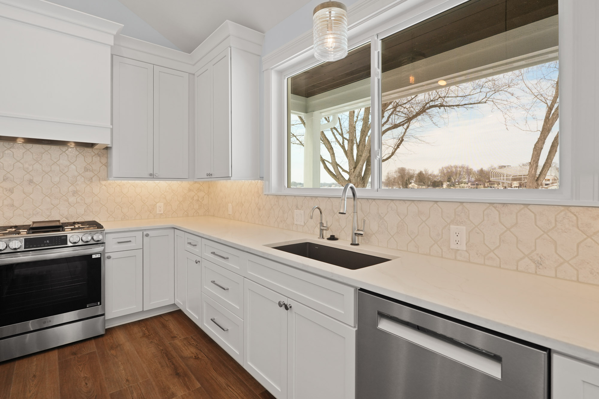 Remodeled white kitchen with quartz countertops and stainless steel appliances.